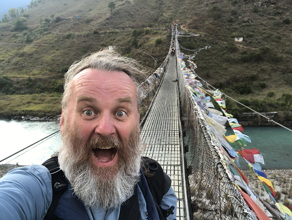 Na zdjęciu uśmiecham się przed wejściem na most Punakha
