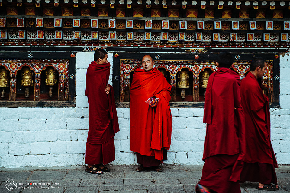 Mnisi odziani w czerwone szaty przechodzą przy modlitewnych młynkach