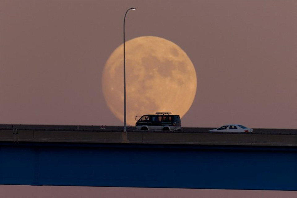Vehicles travel over the Coronado bridge as the moon rises in the distance in Coronado, California, US, August 29, 2023. Image Credit: Reuters