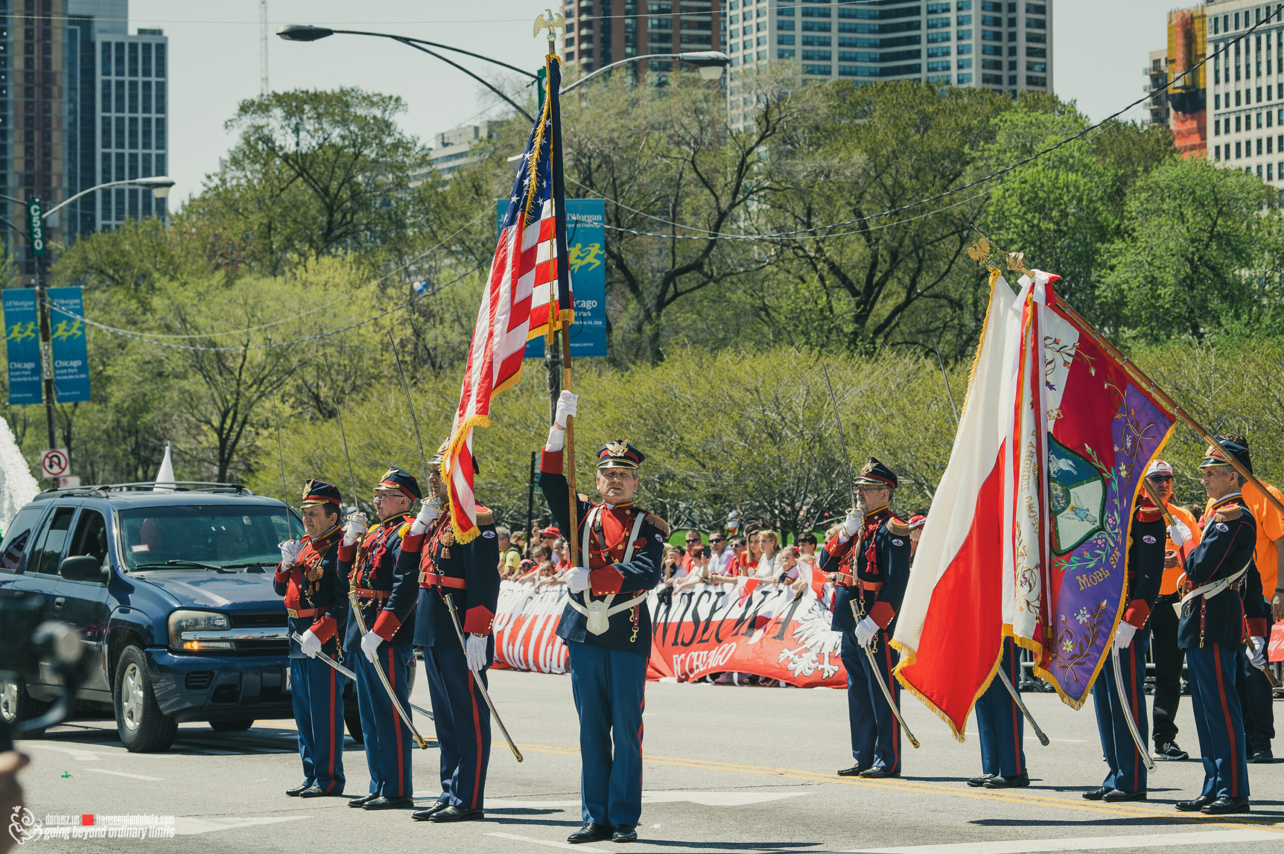 Men in elaborate uniforms hold American and Polish flags at parade.