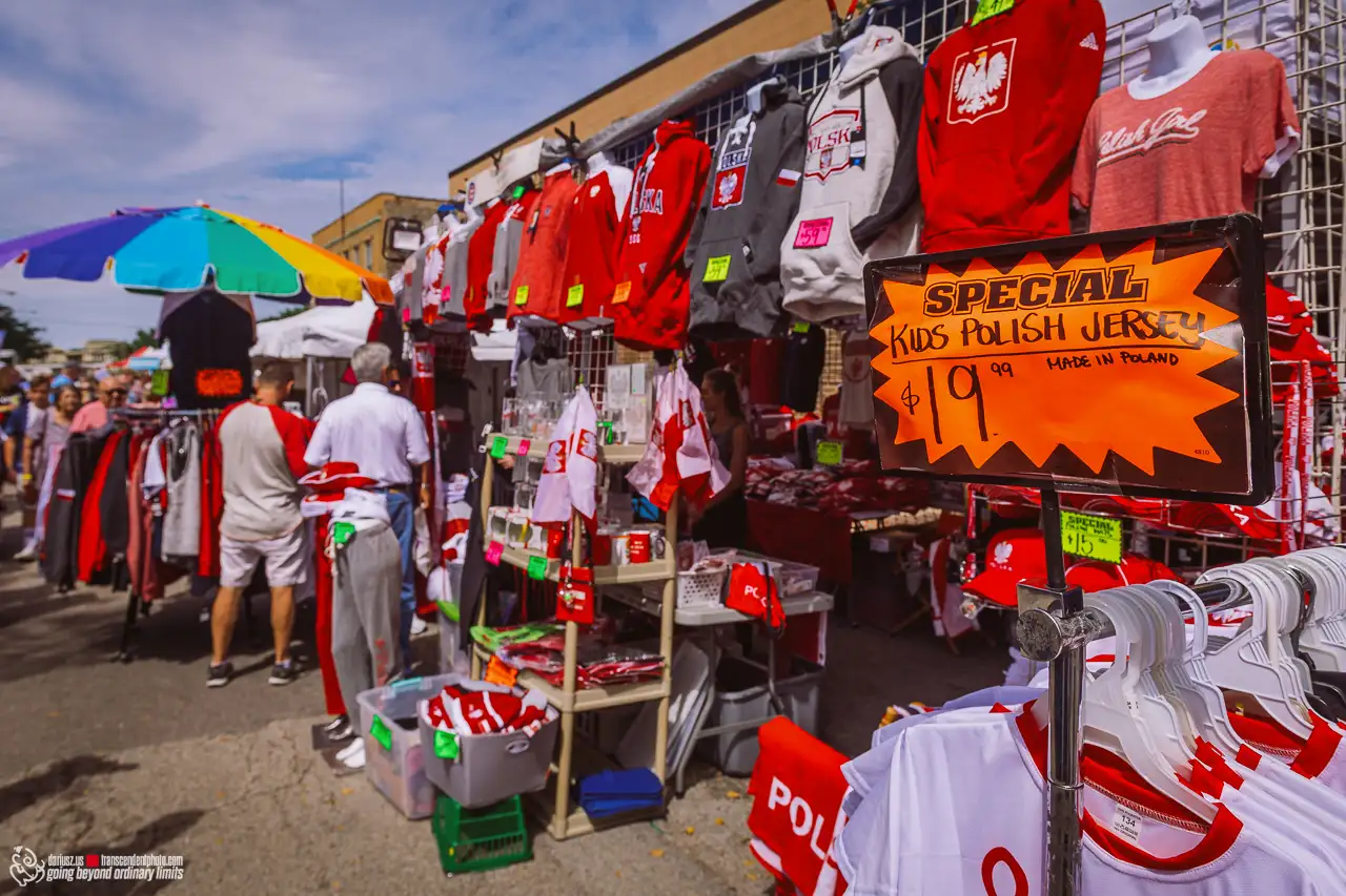Stoisko z polską odzieżą i gadżetami narodowymi podczas festiwalu polonijnego na świeżym powietrzu.