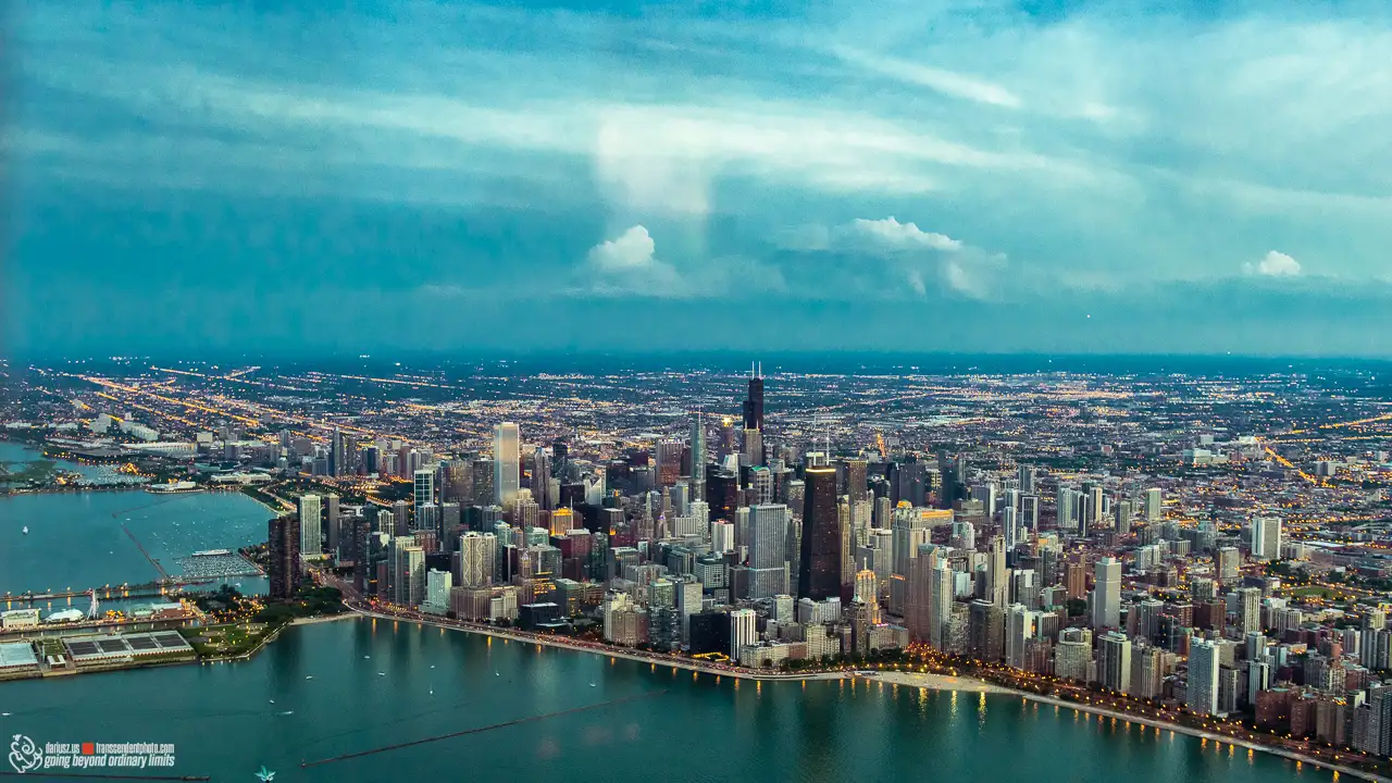 Panorama Chicago z lotu ptaka o zmierzchu, z widocznymi wieżowcami Downtown, linią brzegową jeziora Michigan oraz siatką rozświetlonych ulic miasta.