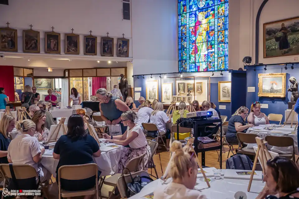 Women painting in a museum art class with stained glass.