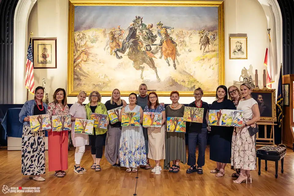 Group displaying paintings in grand hall with large historical artwork.