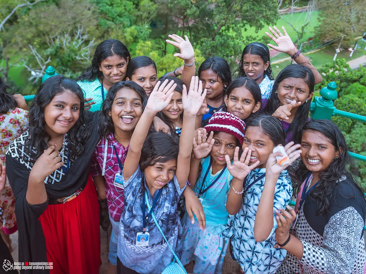 Group of smiling young girls waving joyfully outdoors.