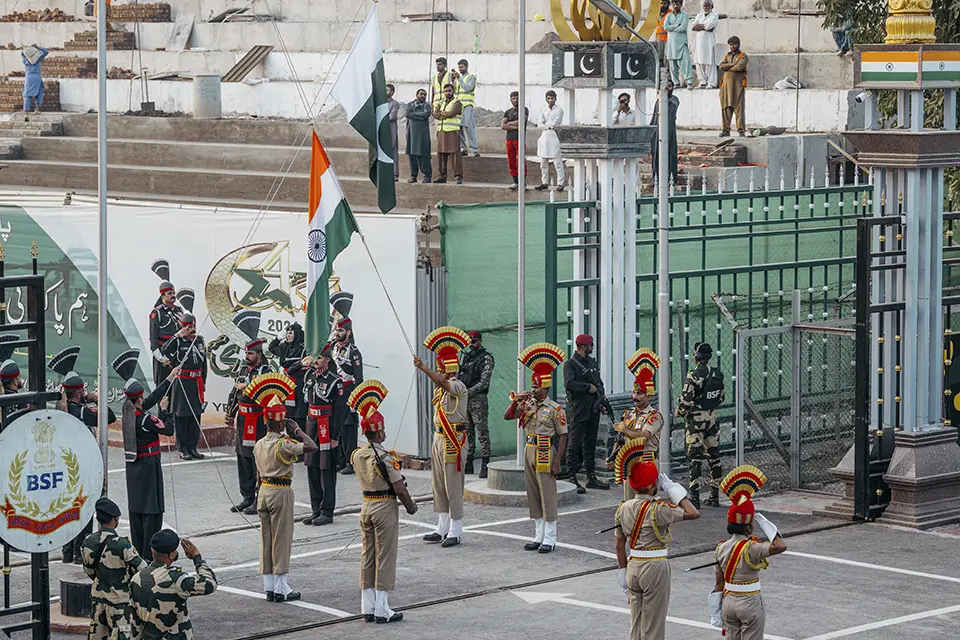 Indian and Pakistani soldiers at border ceremony with national flags.