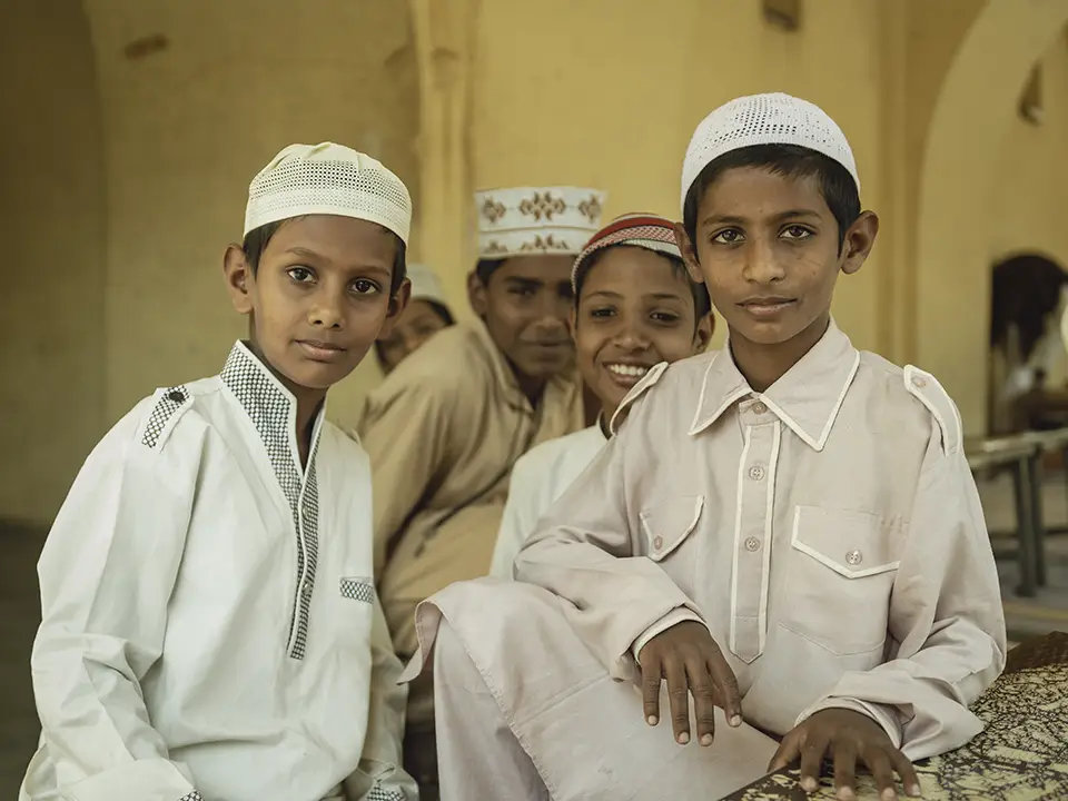Group of young Muslim boys in traditional attire with kufis.