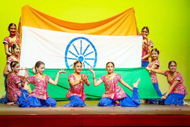 Young Indian dancers in traditional dress before national flag.