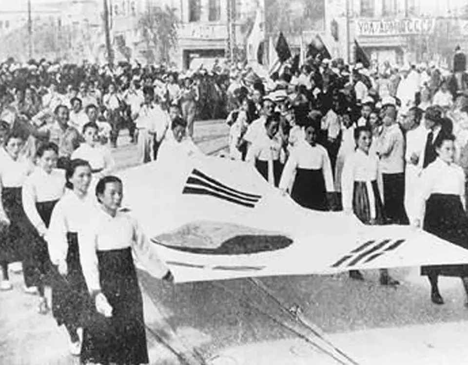 Korean women carry large flag during historical demonstration.