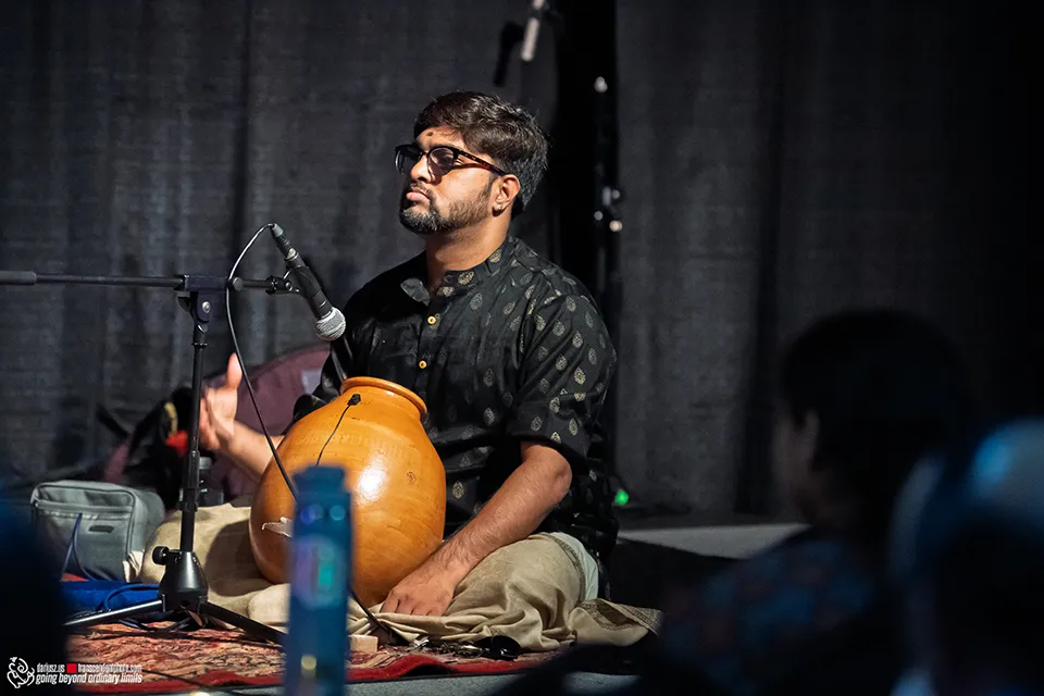 Man playing traditional Indian Ghatam percussion instrument on stage.