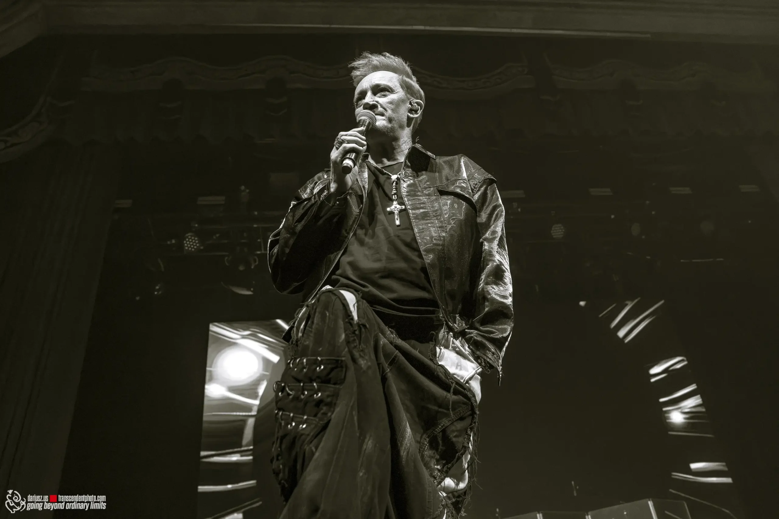 Rock singer performs on stage with microphone in black and white.
