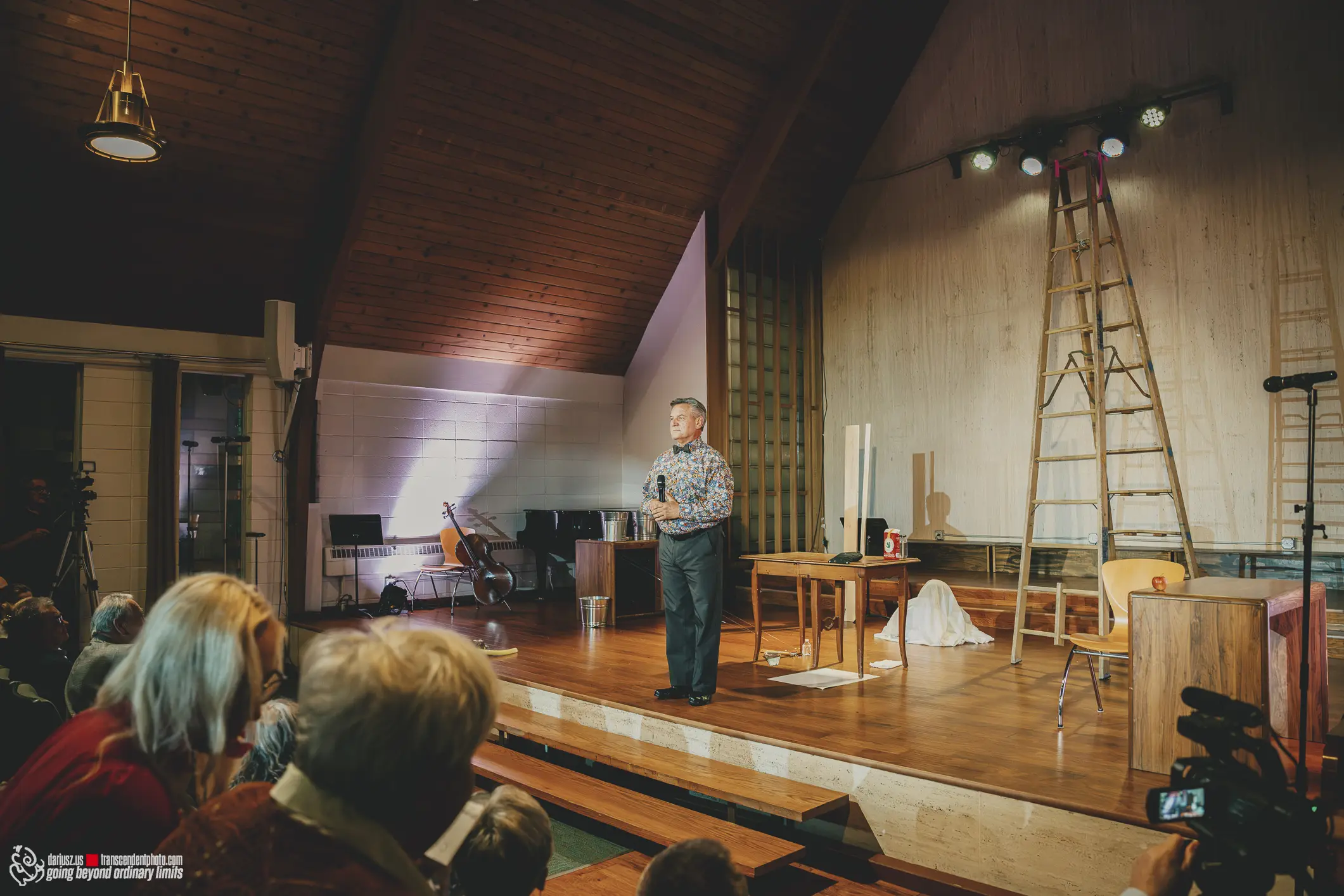 Man speaking on stage to an audience at an indoor event.