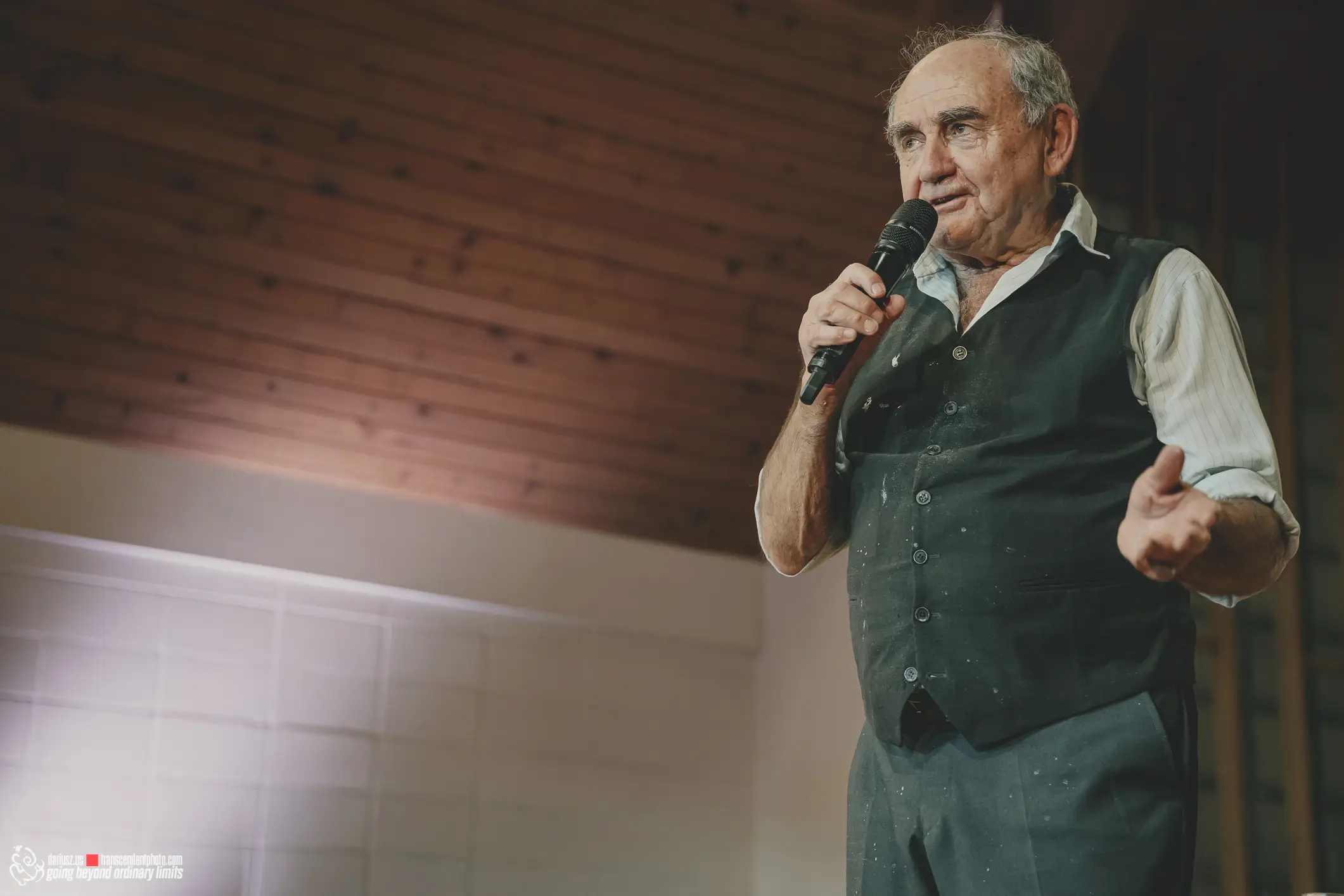 Jan Peszek speaking into microphone at a presentation.
