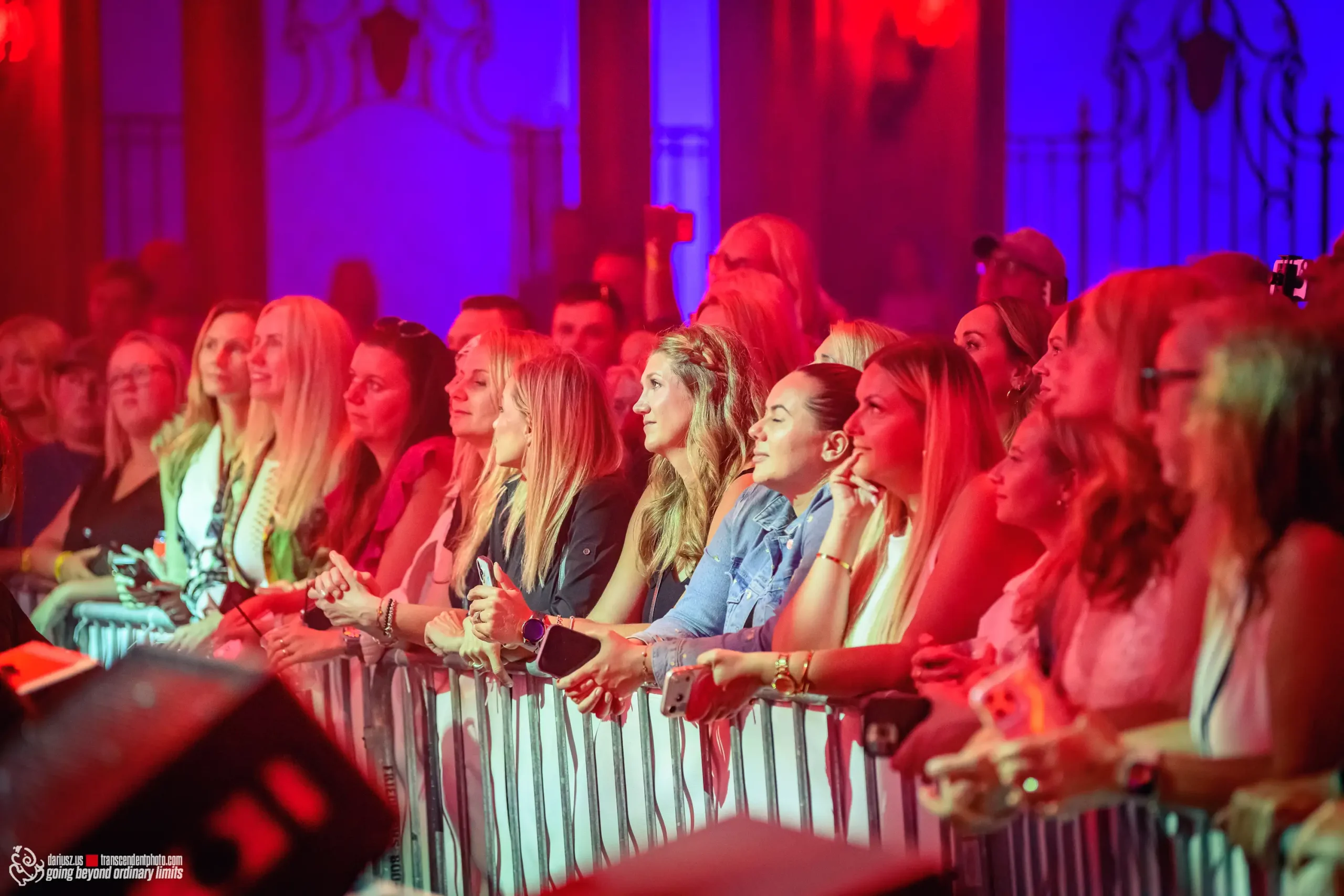Audience at a concert under vibrant red and blue lights.