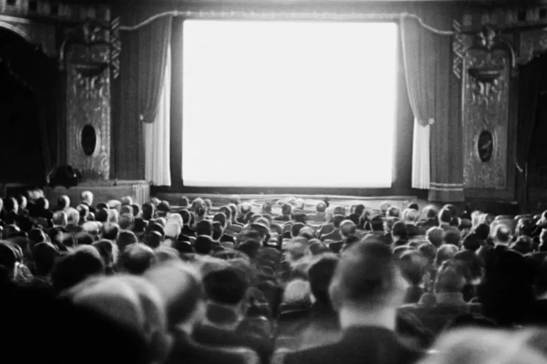 Audience watching a blank screen in a grand movie theater.