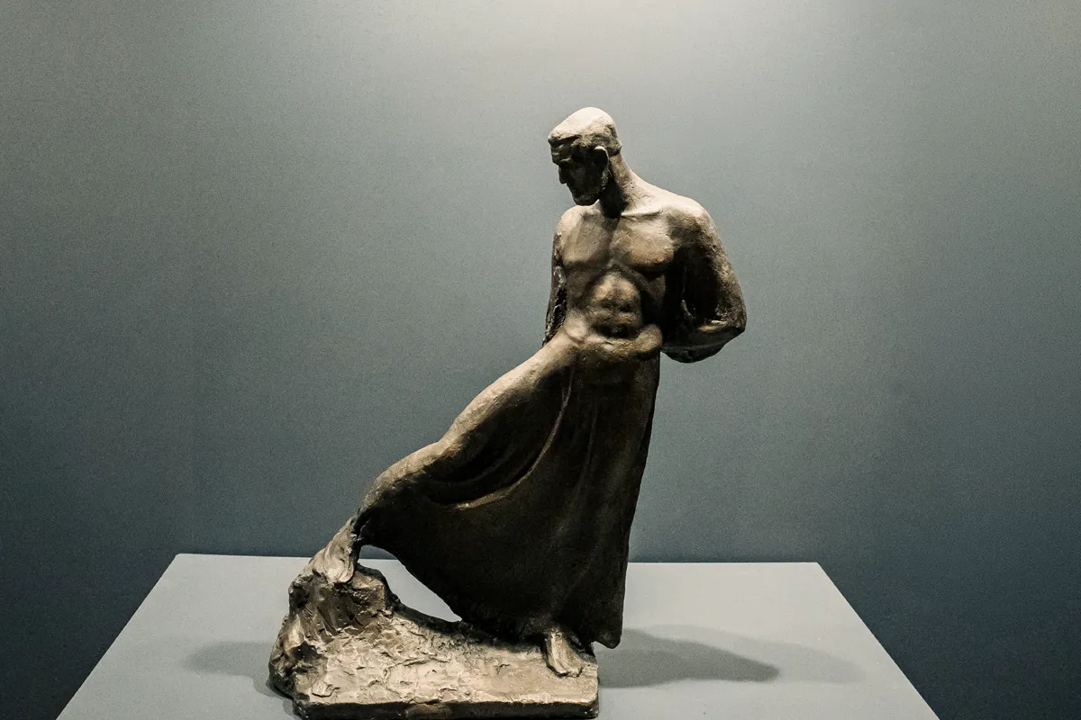 Bronze sculpture of a draped male figure on a pedestal.