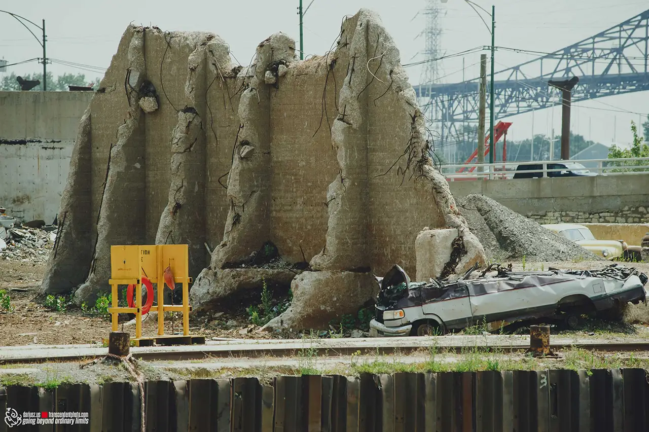 Demolished concrete structure, overturned van, and urban debris by water.